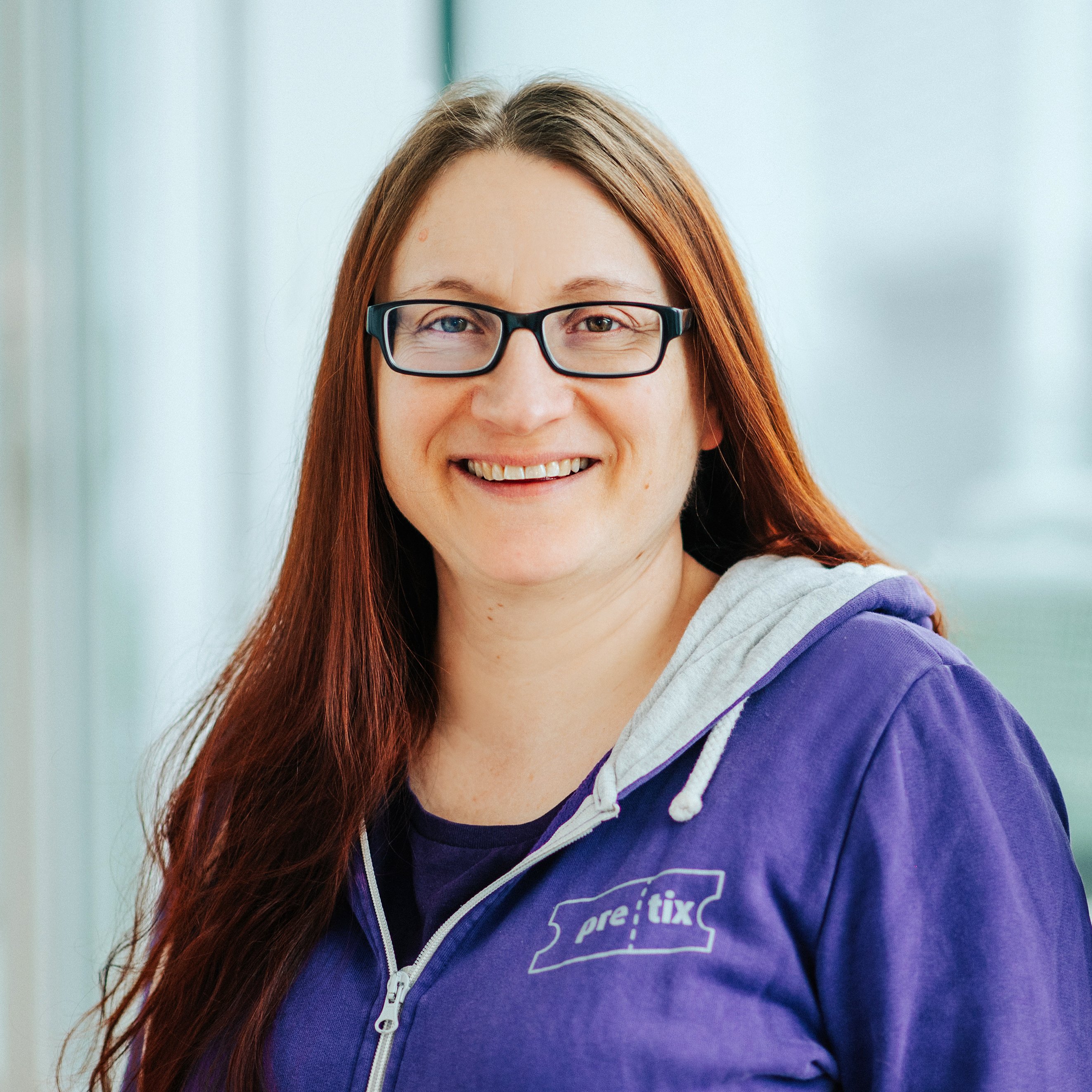 Susanne Kasper aus dem Venueless-Team. Susanne trägt einen pretix Hoodie und lächelt in die Kamera.